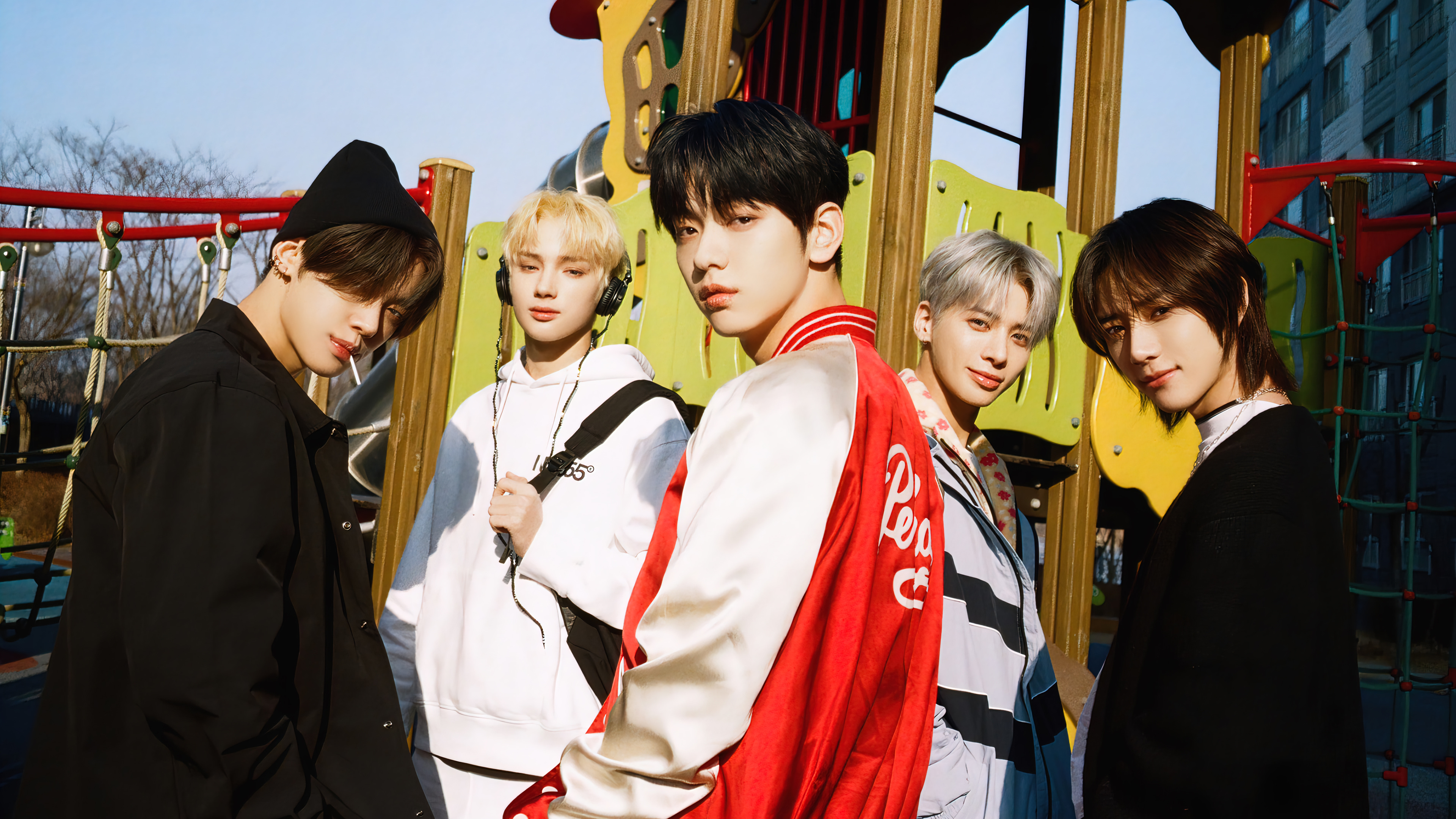 Tomorrow X Together, Soobin in red jacket, Yeonjun wearing beanie, Huening Kai with headphones, Outdoor playground structure, 4K Desktop wallpaper