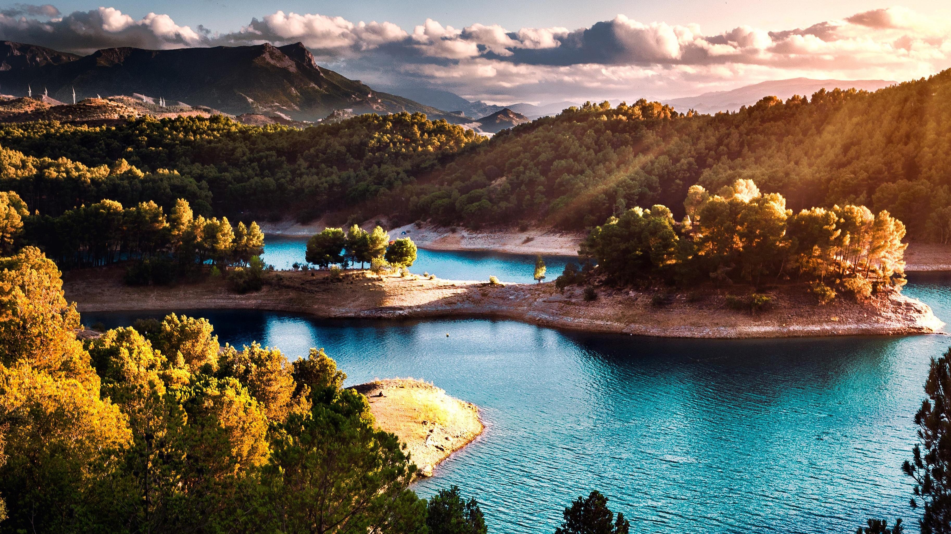 Turquoise winding reservoir, Sunlit pine forested peninsula, Mountain range with sunbeams, HD Desktop wallpaper