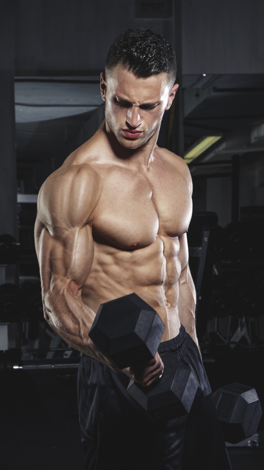 Muscular male bodybuilder, Black hex dumbbell, Dimly lit gym setting, Full HD Phone wallpaper