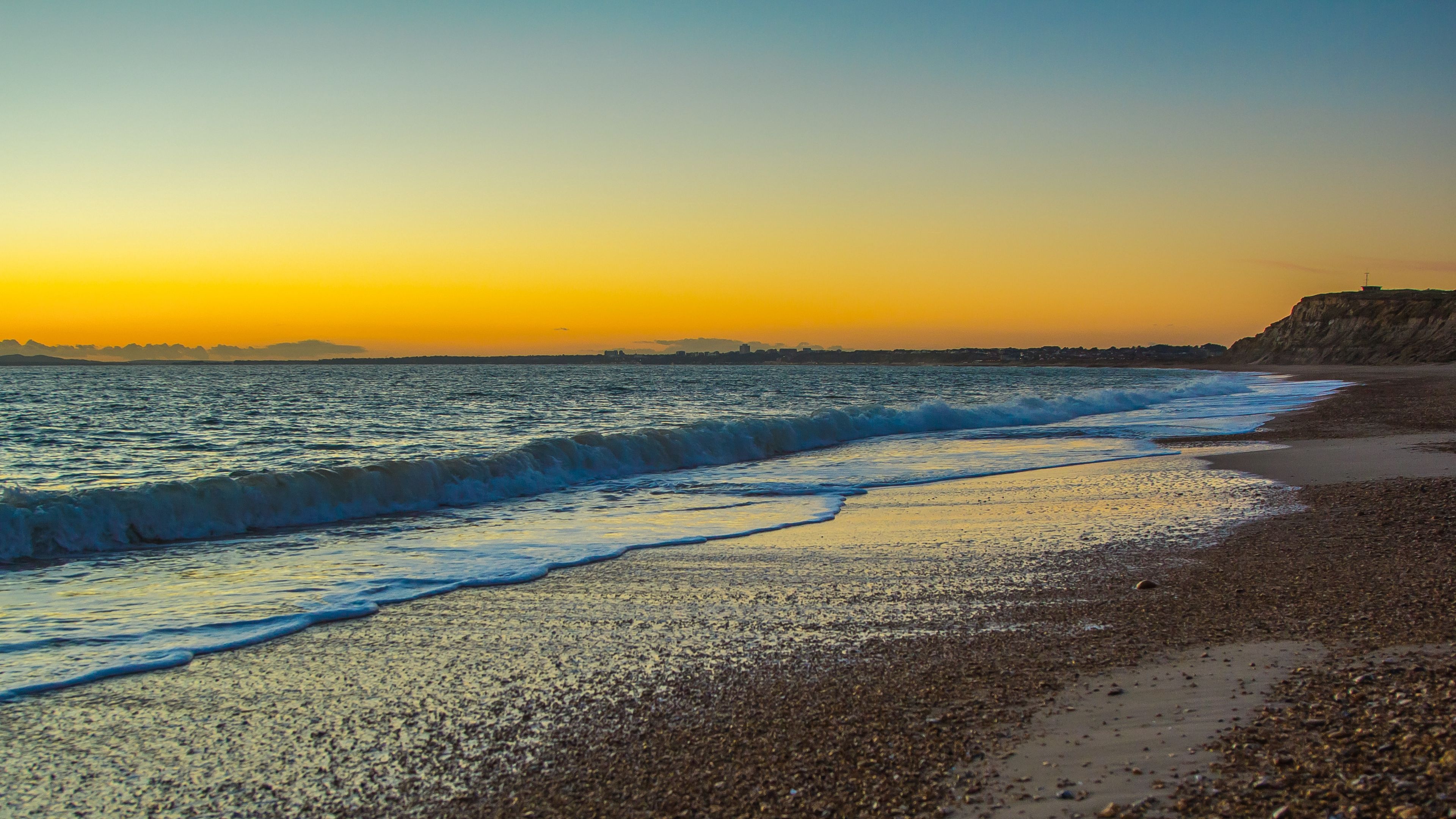 shingle beach shoreline, incoming ocean surf, golden sunset horizon, 4K Desktop wallpaper