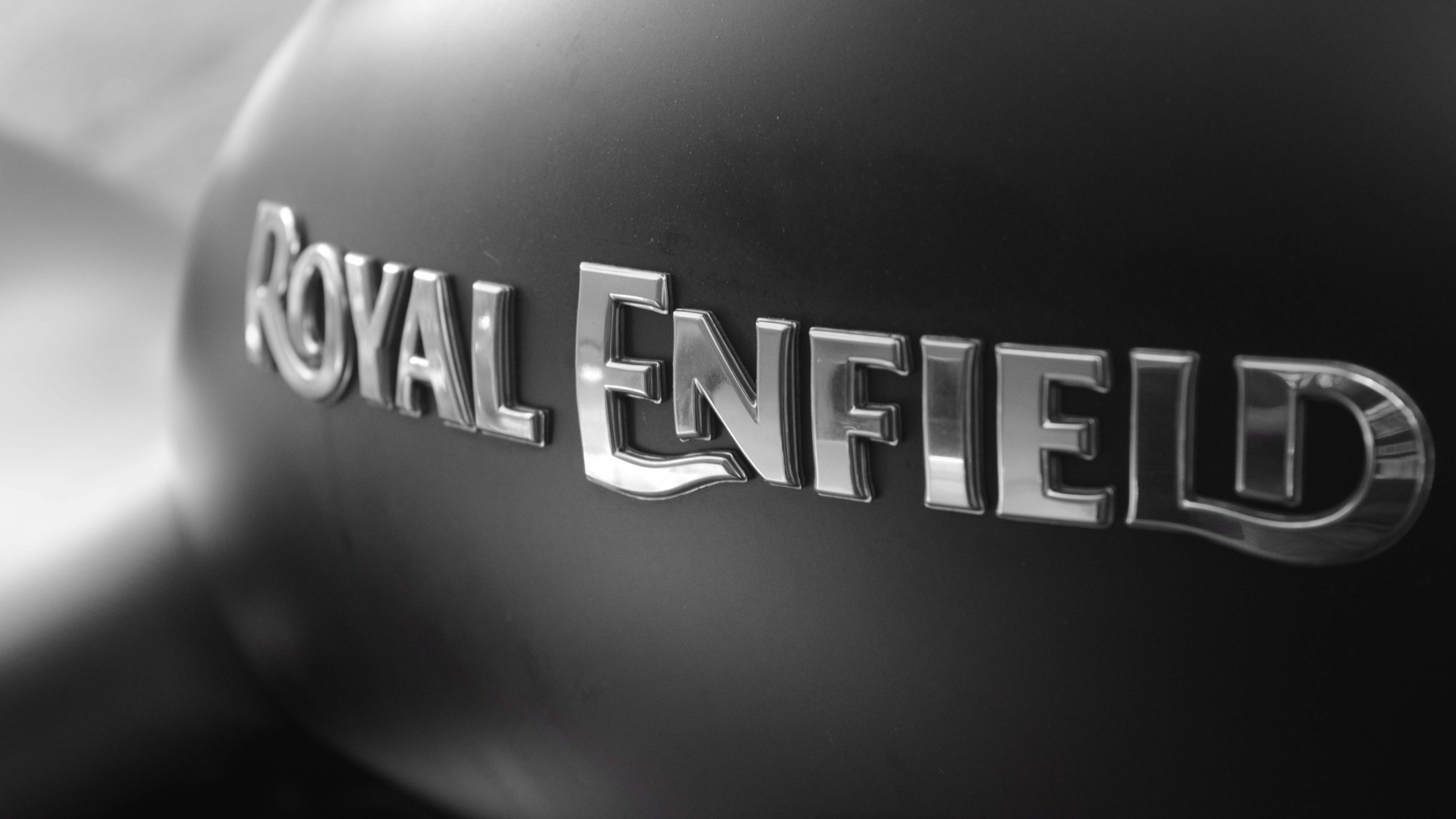 ROYAL ENFIELD text, matte black motorcycle tank, chrome Royal Enfield badge, 4K Desktop wallpaper