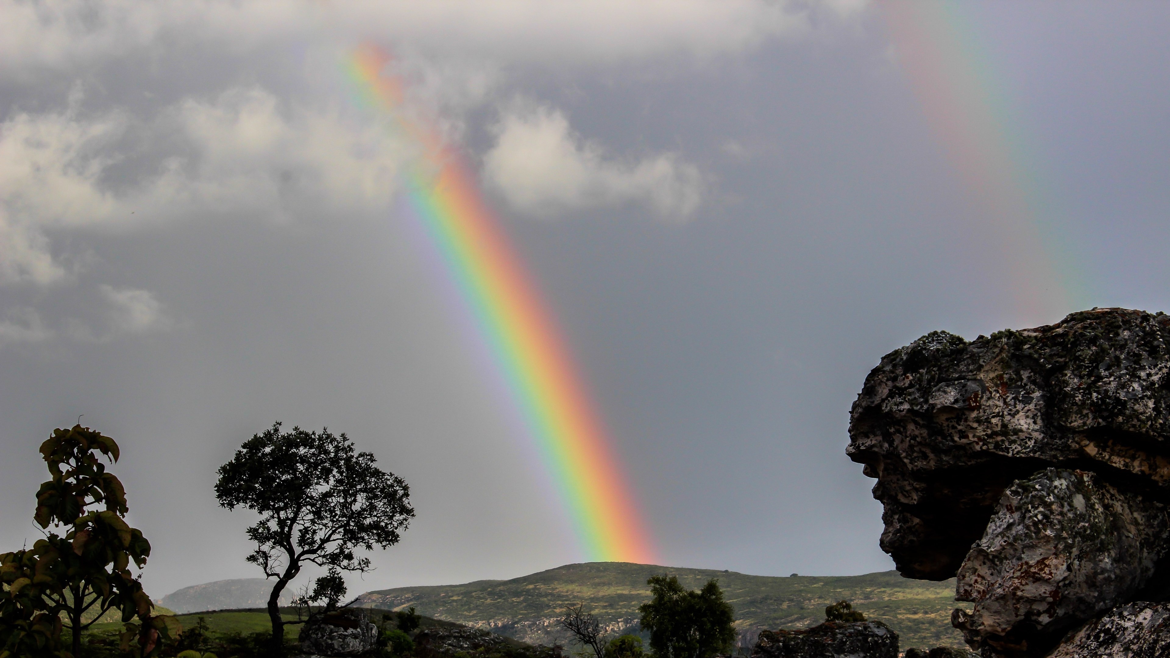 Vibrant natural rainbow, Weathered rock outcrop, Rolling green hillside, 4K Desktop wallpaper
