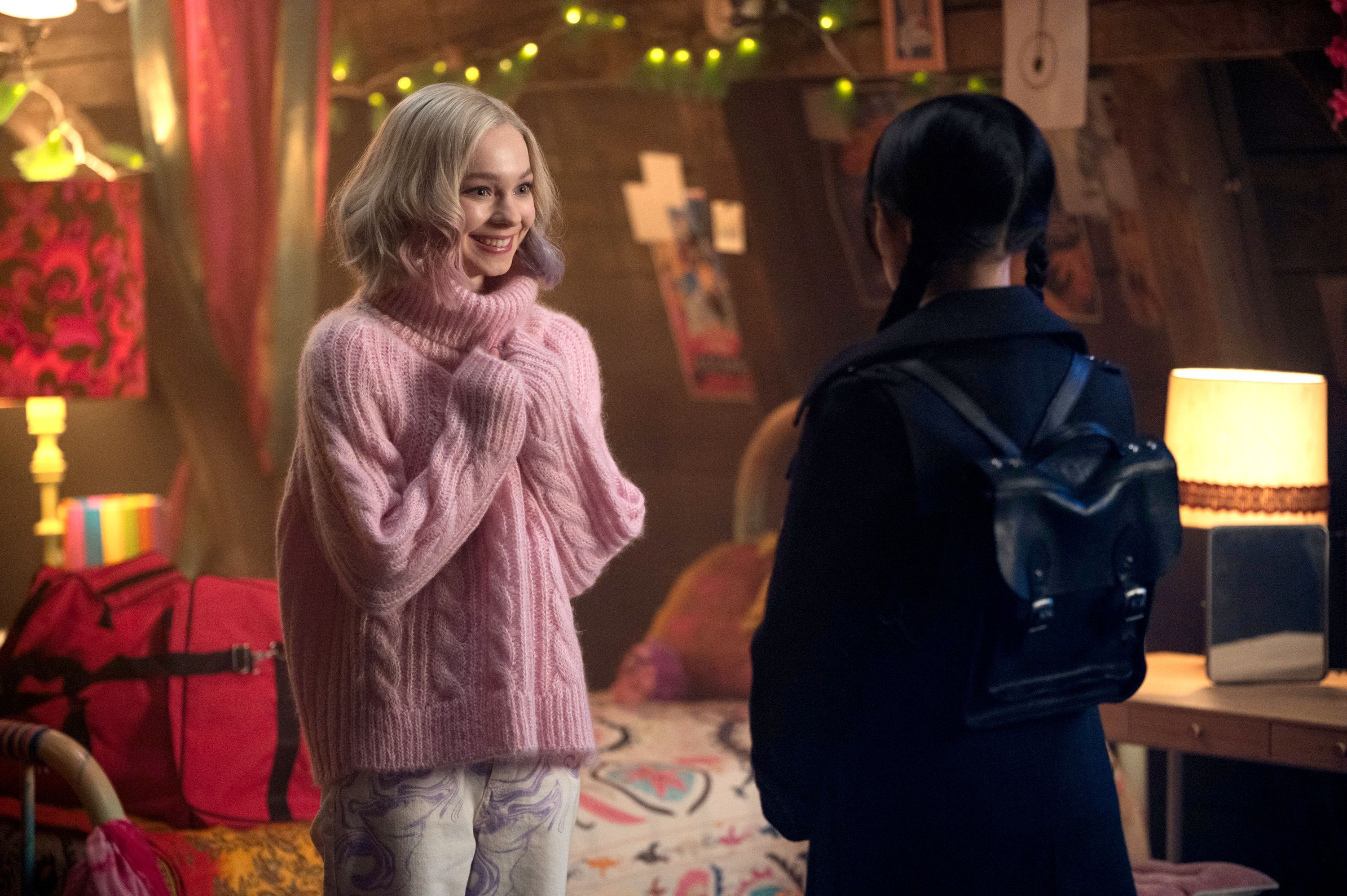 Emma Myers as Enid Sinclair, Wednesday Addams seen from behind, Pink cable knit turtleneck, Fairy-lit dorm room, HD Desktop wallpaper