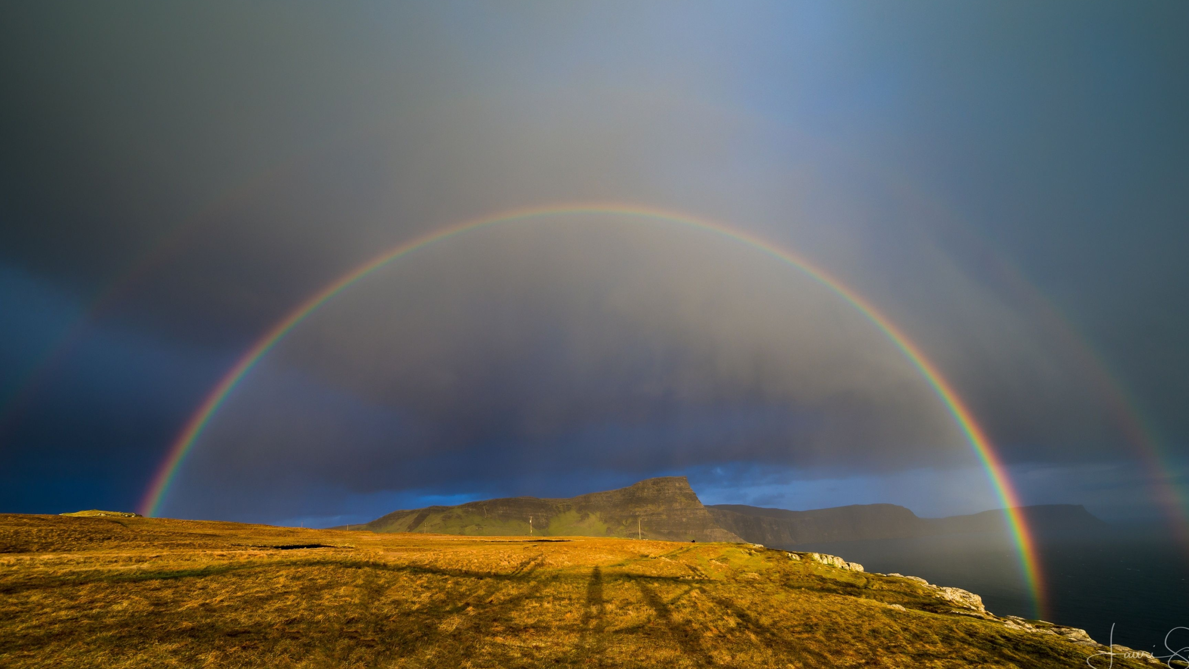 Full arch rainbow, Grassy coastal cliff, Dark storm clouds, 4K Desktop wallpaper