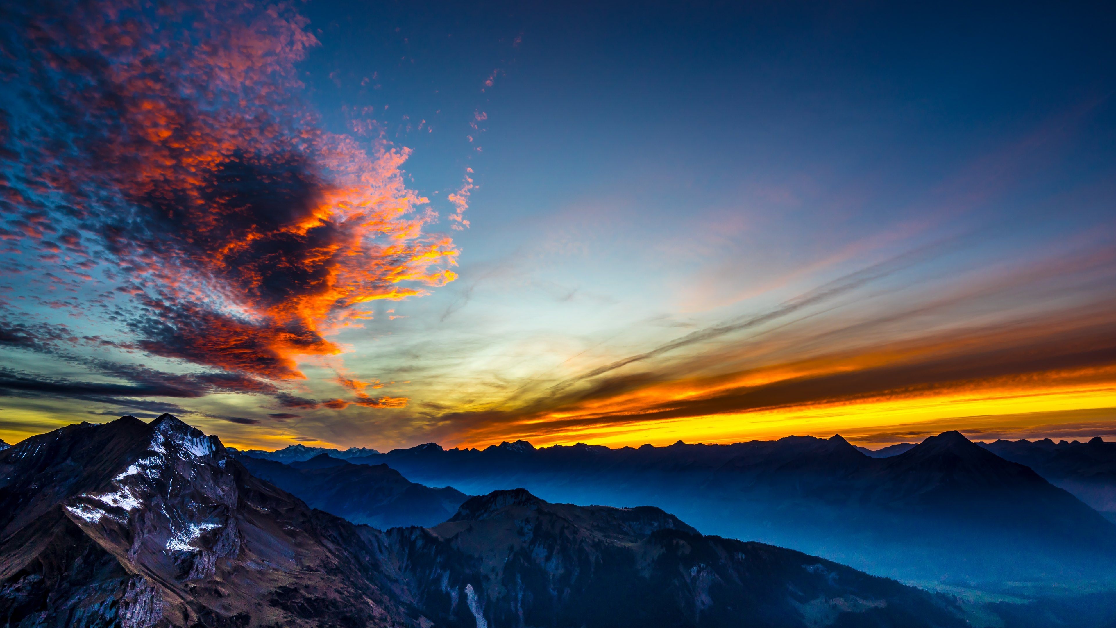 jagged rocky mountain peaks, fiery sunset clouds, golden twilight horizon, 4K Desktop wallpaper