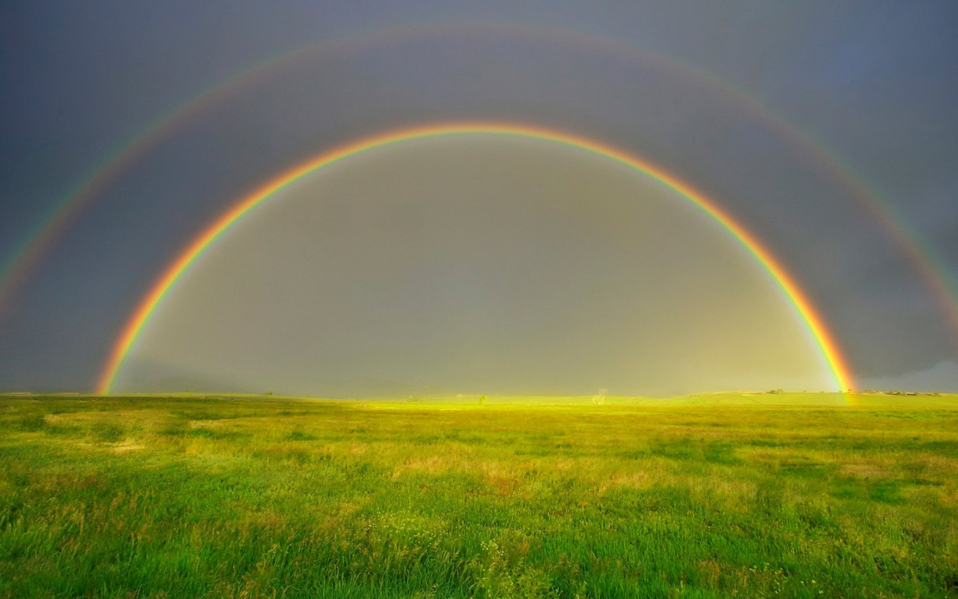 Vivid double rainbow arc, Lush green grassland field, Dark stormy sky, HD Desktop wallpaper