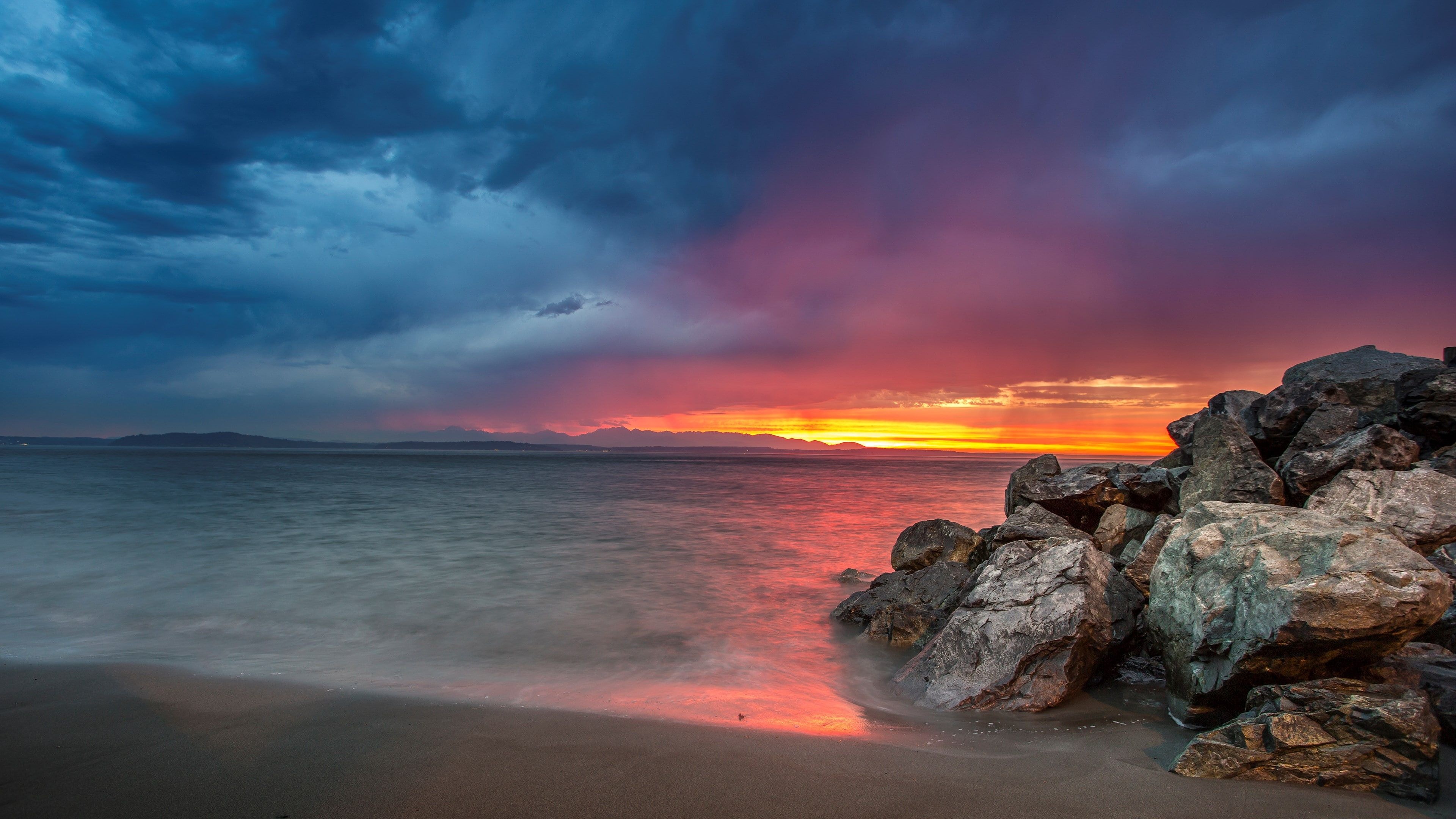 rocky beach shoreline, vibrant sunset horizon, stormy dusk sky, 4K Desktop wallpaper