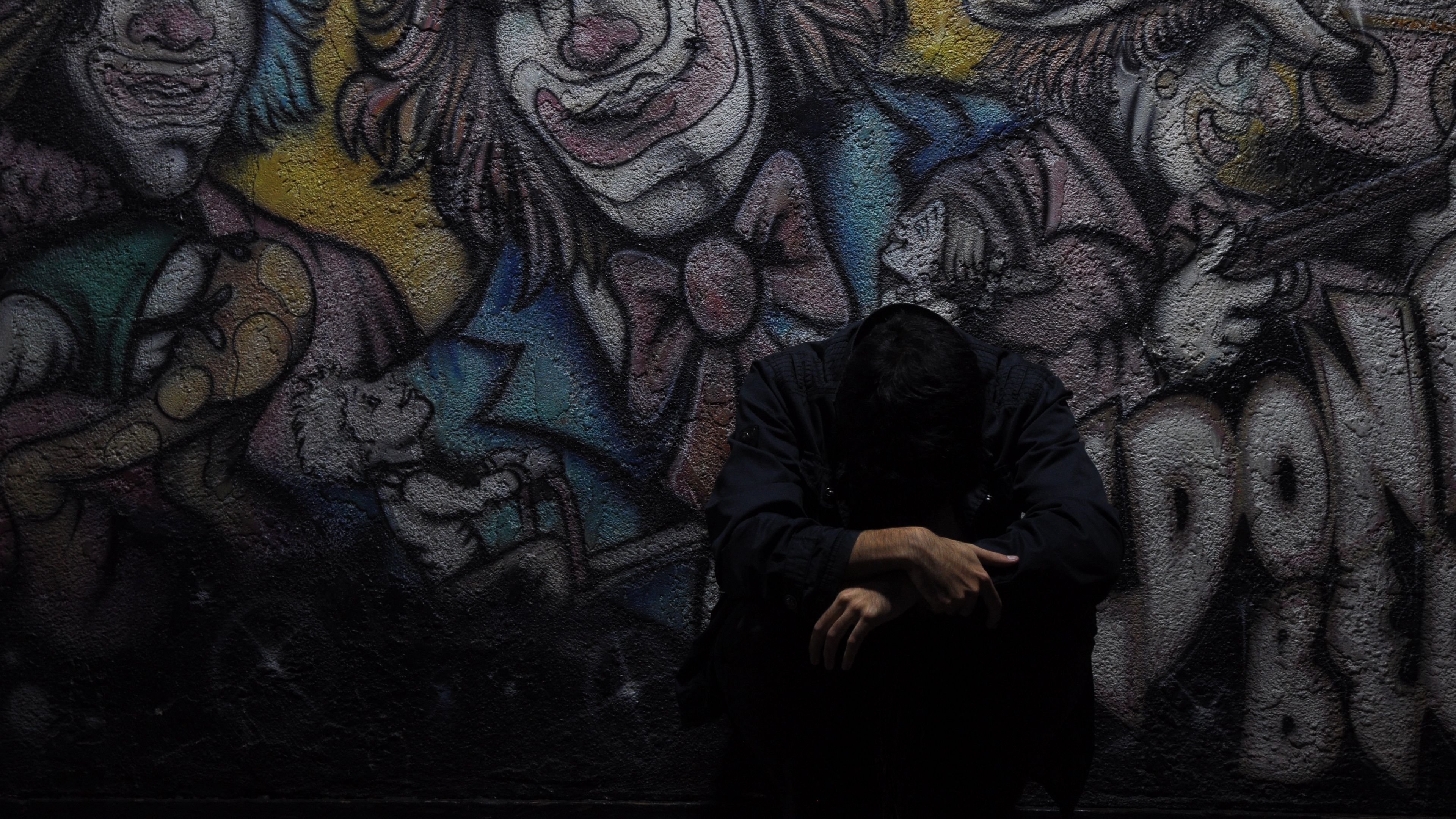 Slumped sad person, Clown graffiti mural, Dark moody lighting, 4K Desktop wallpaper