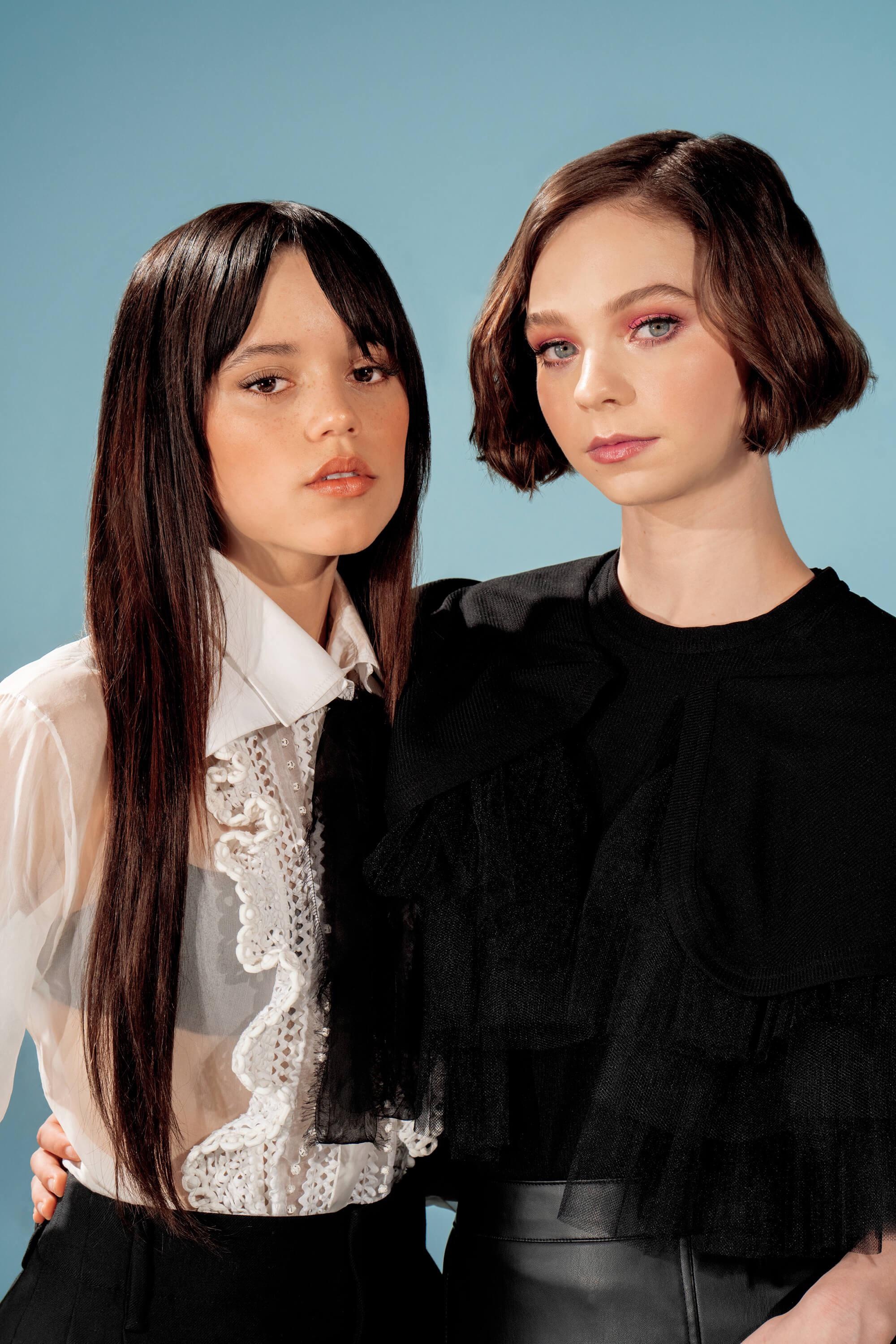 Emma Myers in black ruffled top, Jenna Ortega in sheer white blouse, Black leather skirt, Pale blue studio backdrop, HD Phone wallpaper