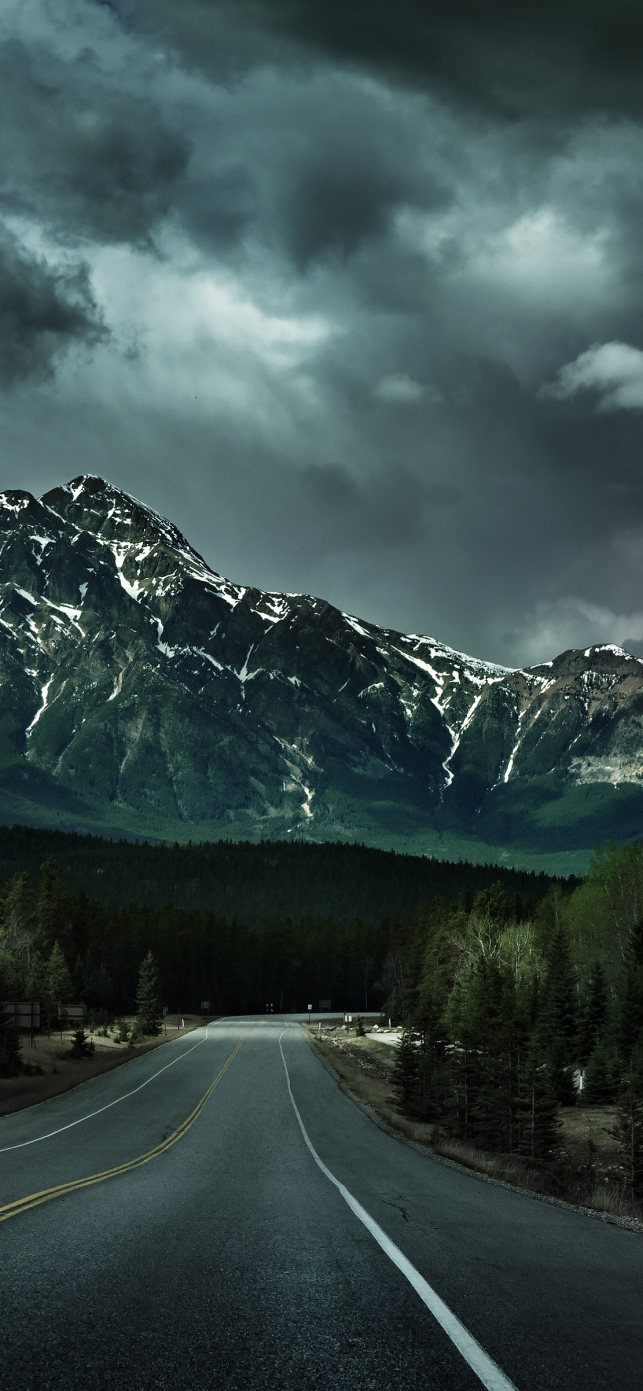 two-lane mountain highway, snow-dusted rocky peak, dark stormy clouds, HD Phone wallpaper