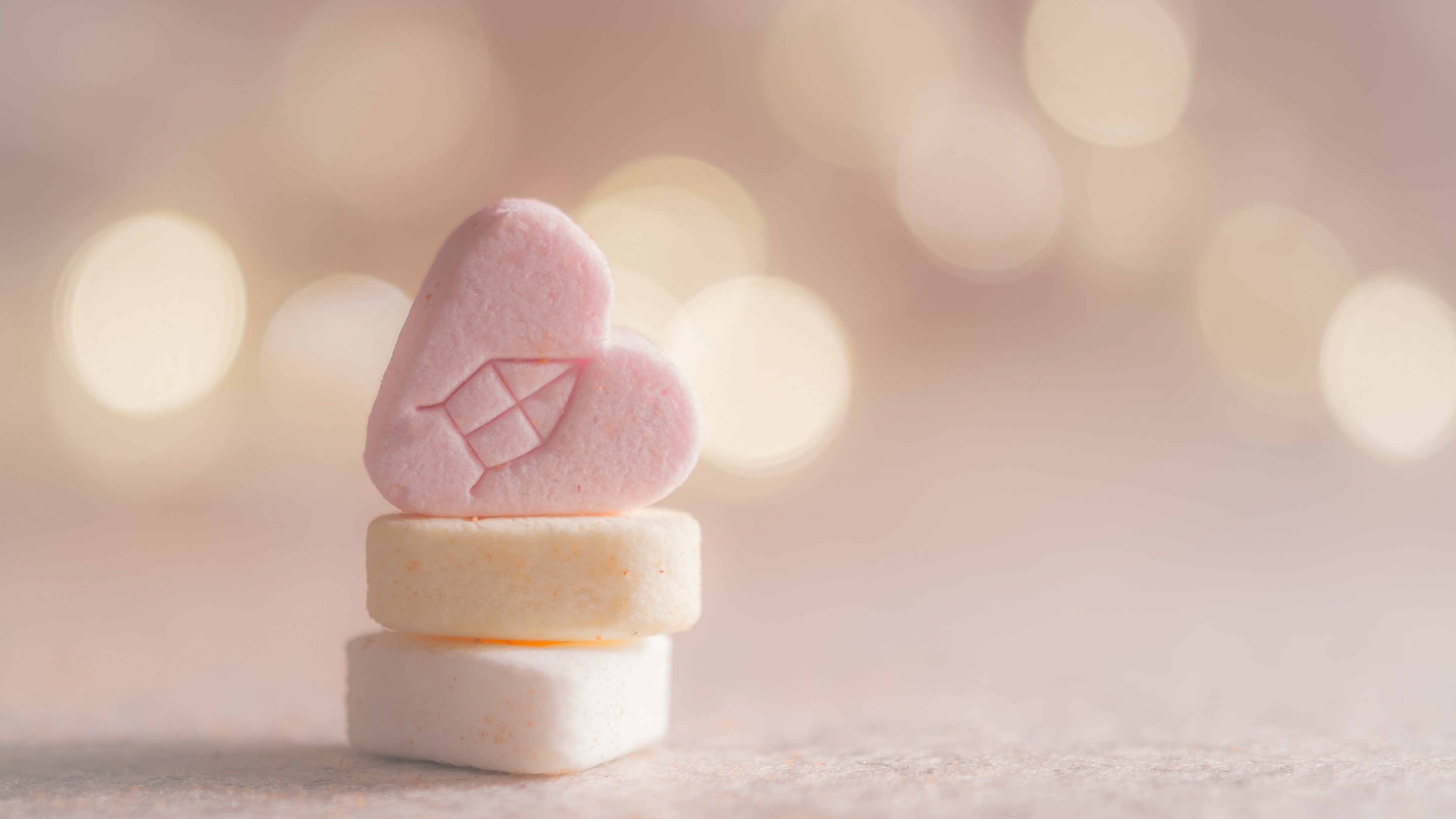 embossed pink candy heart, stacked pastel candy tablets, warm bokeh lights, 4K Desktop wallpaper