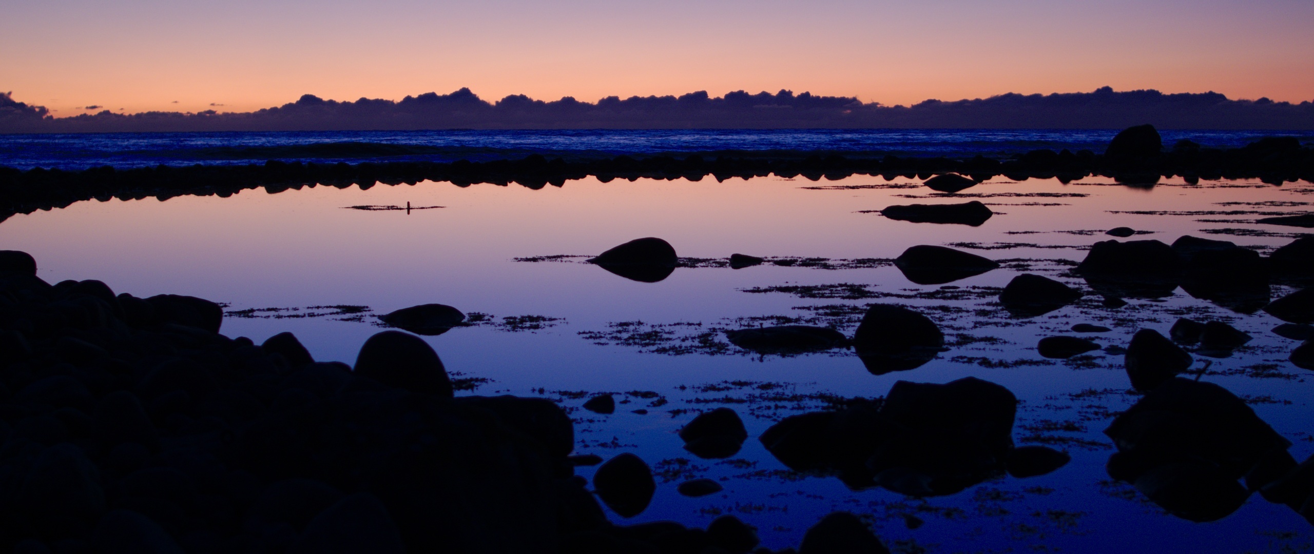 coastal tidal pool, silhouetted shoreline boulders, twilight sea horizon, Dual Screen Desktop wallpaper