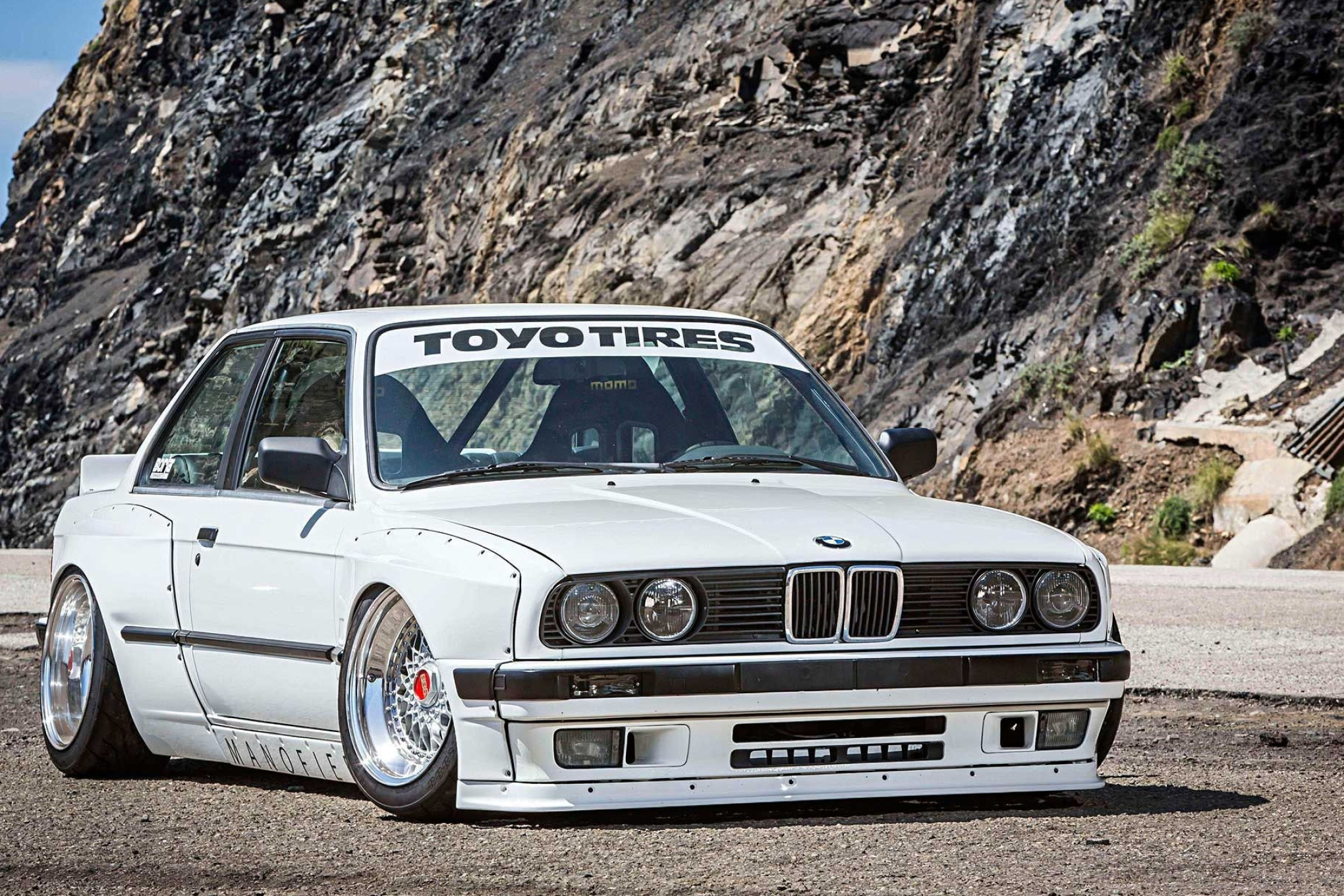 white widebody BMW E30, TOYO TIRES windshield banner, rocky cliffside road, HD Desktop wallpaper