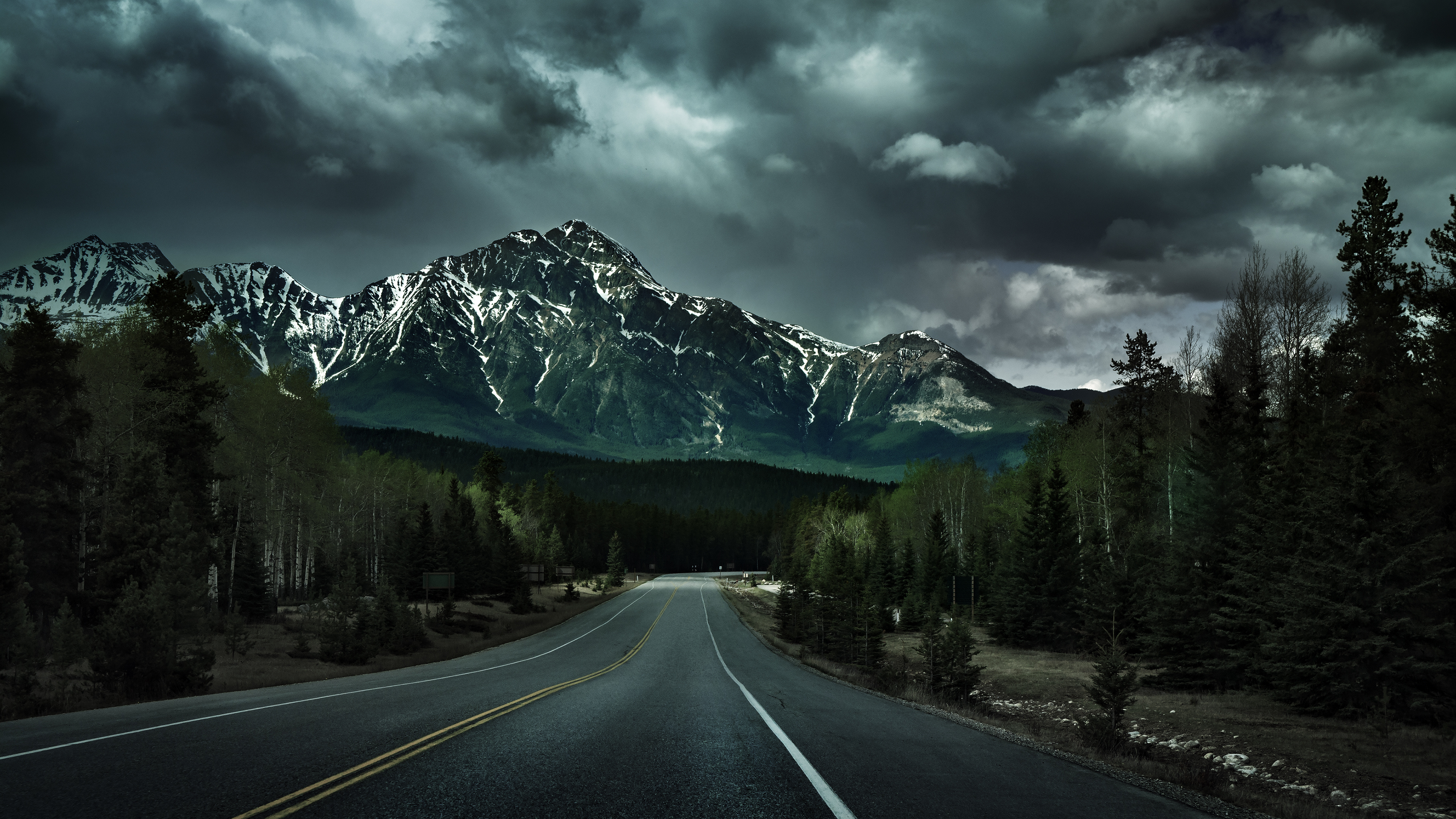 empty mountain highway, snow-capped rocky peak, dark dramatic storm clouds, 4K Desktop wallpaper