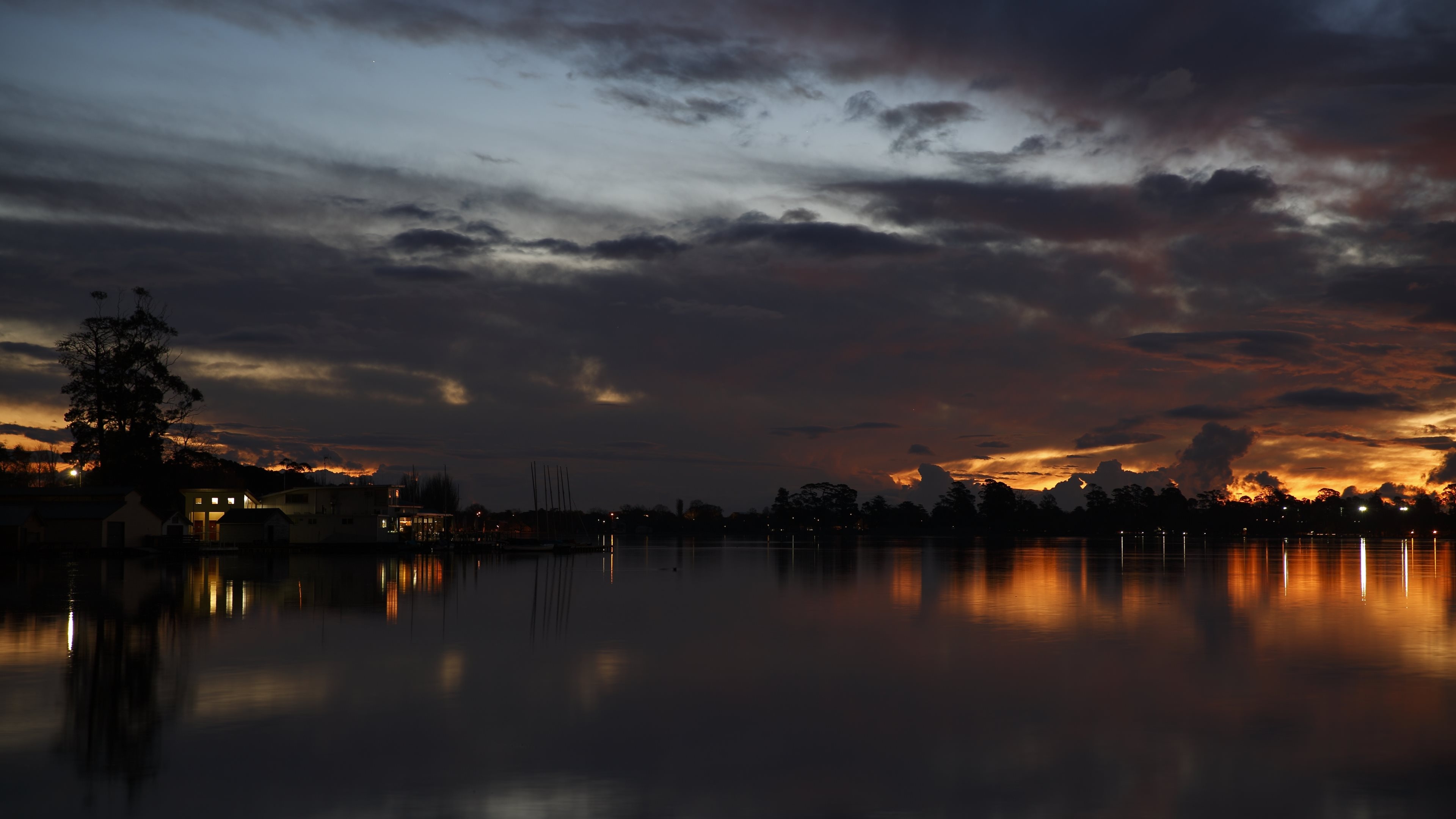 lakefront illuminated houses, calm lake reflections, dramatic sunset clouds, 4K Desktop wallpaper
