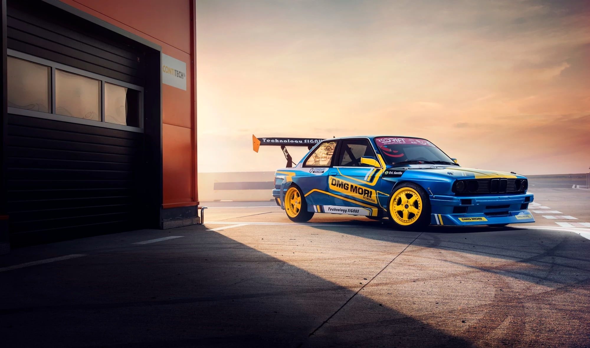 BMW E30 drift car, DMG MORI livery, racetrack garage at sunset, HD Desktop wallpaper