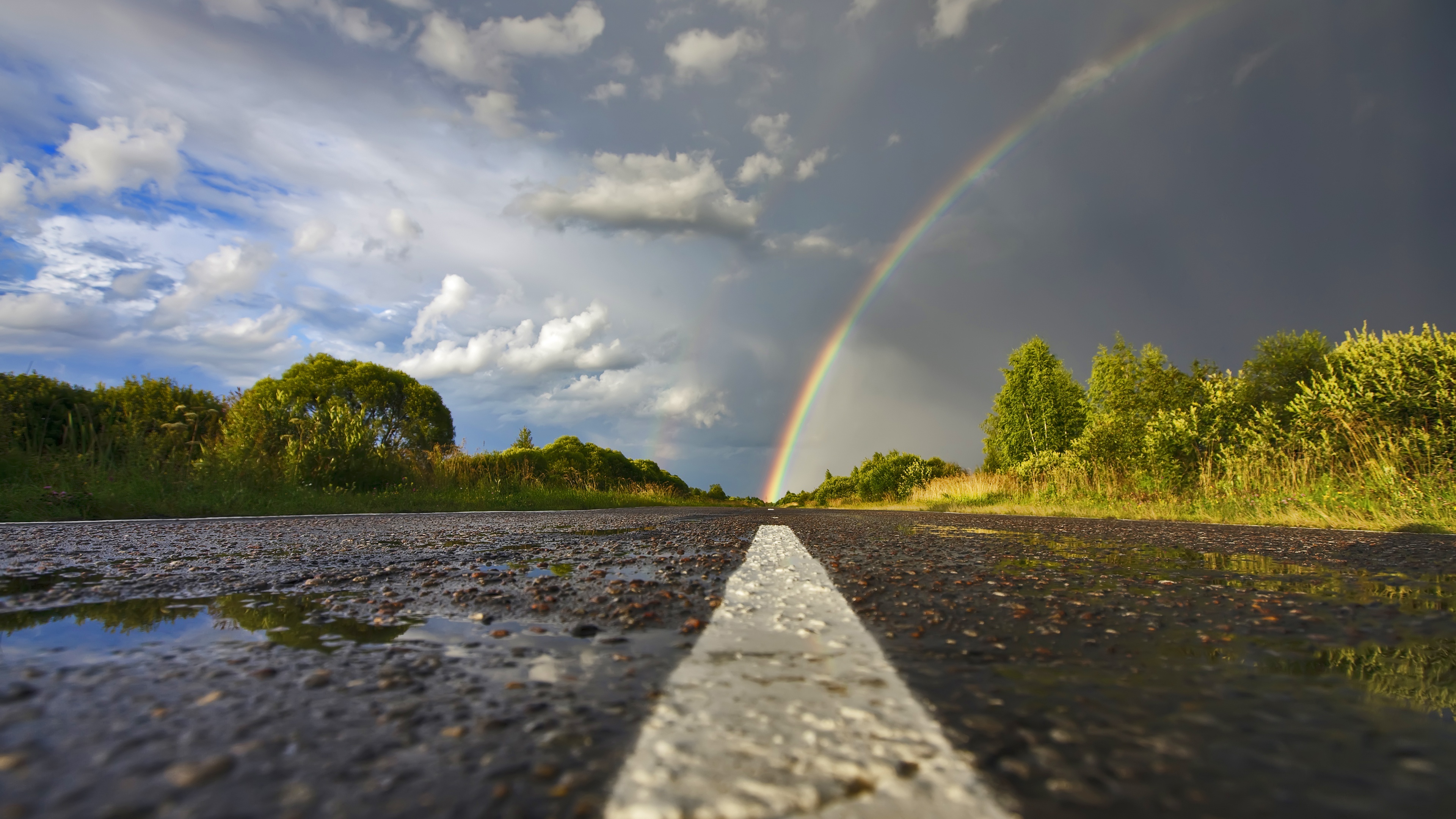 Vibrant rainbow arc, Wet asphalt country road, Dark storm cloud sky, 4K Desktop wallpaper