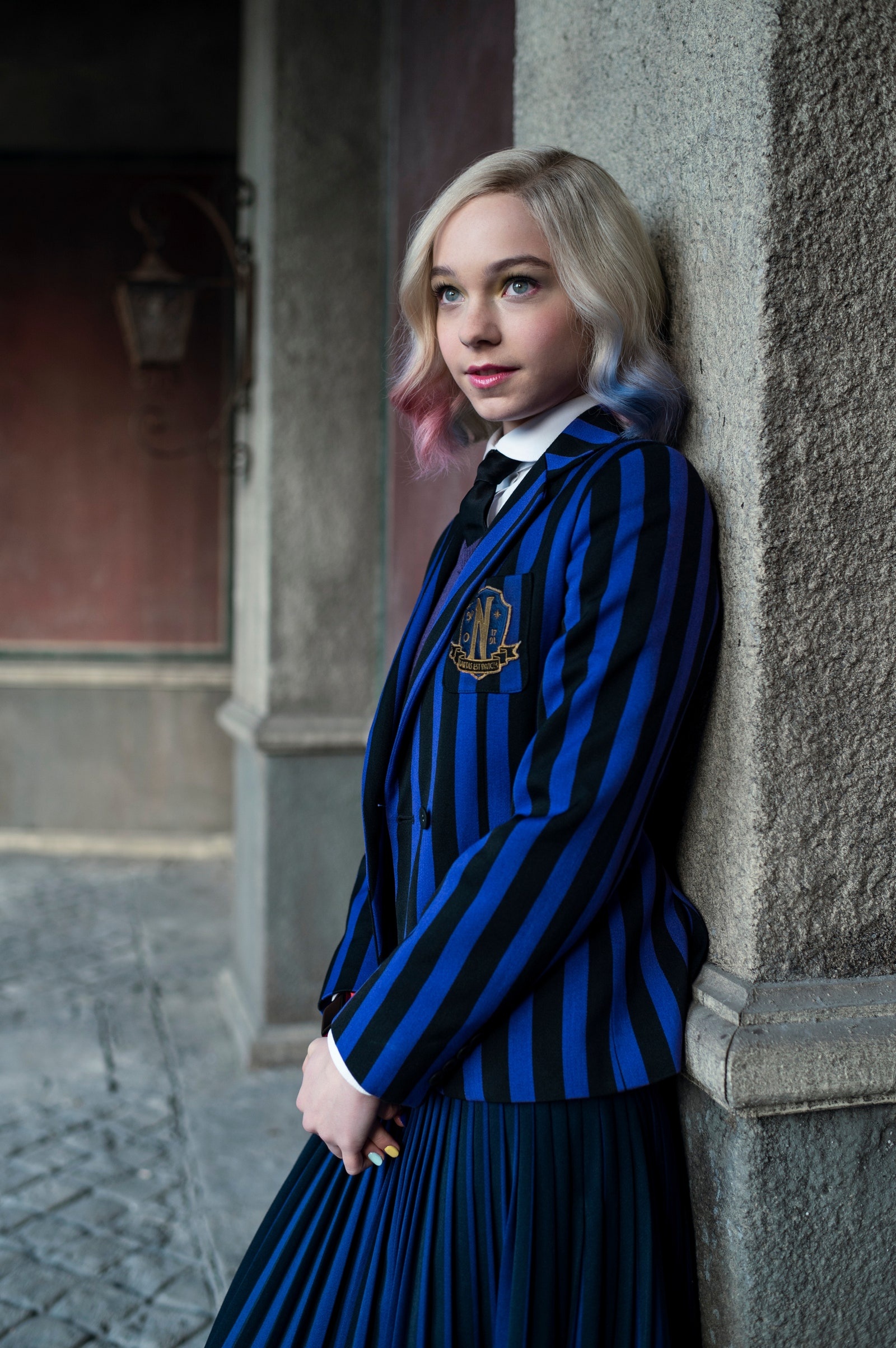 Emma Myers as Enid Sinclair, Nevermore Academy striped blazer, Stone archway courtyard, HD Phone wallpaper