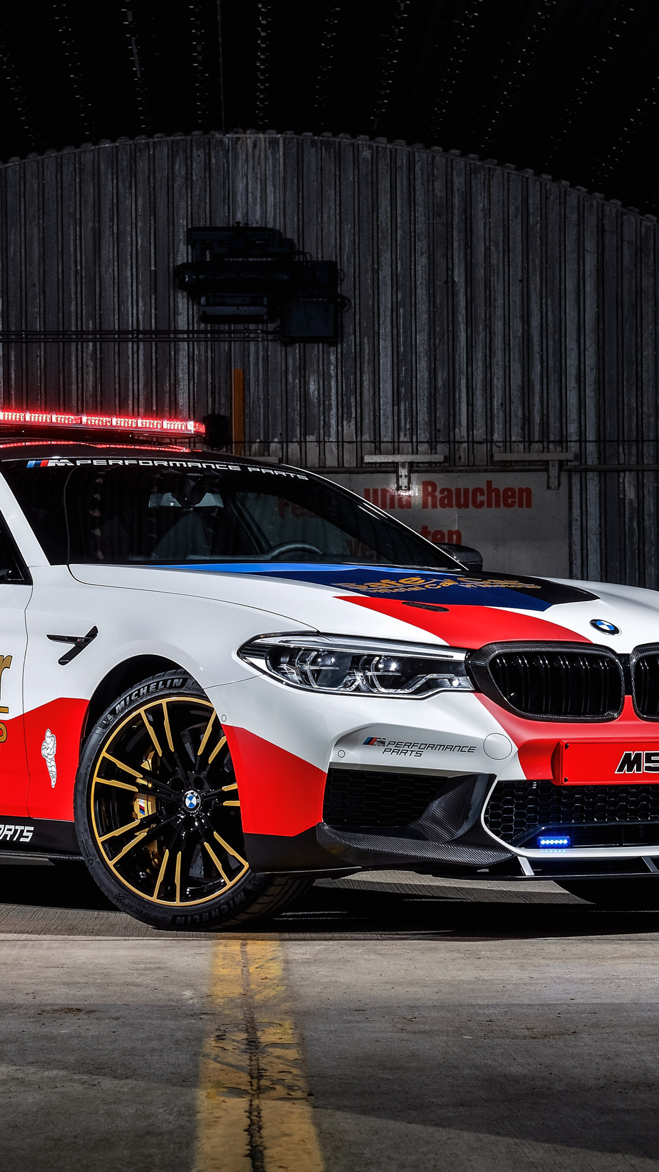 BMW M5 MotoGP Safety Car, Red emergency roof lightbar, Corrugated metal hangar, 4K Phone wallpaper