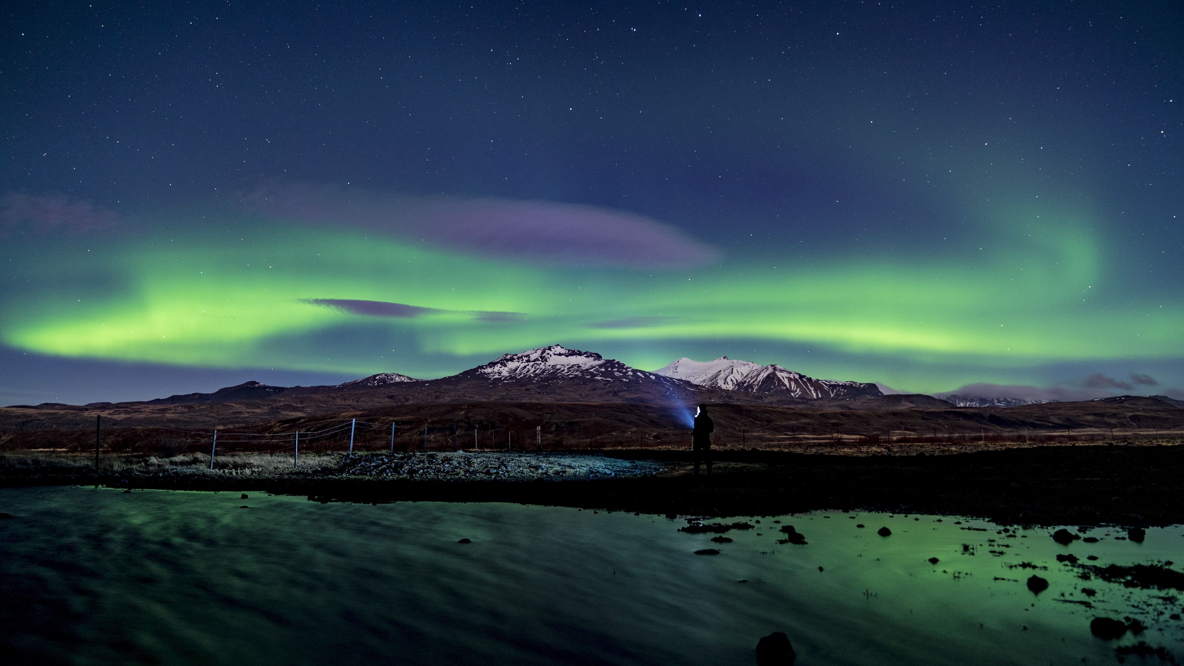 Green Aurora borealis, Snow-capped mountain ridge, Person holding flashlight, 4K Desktop wallpaper