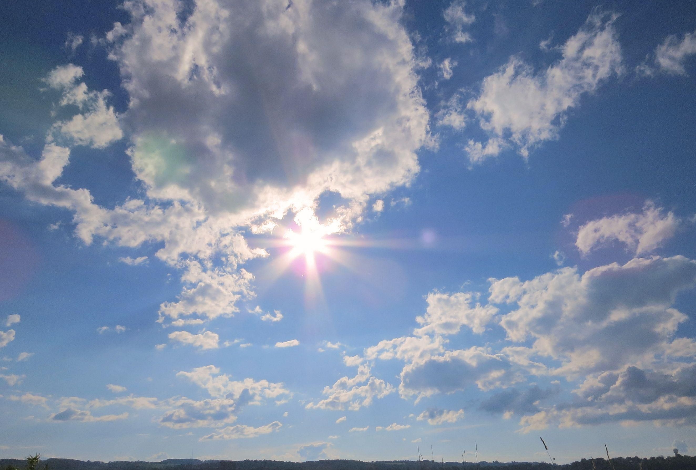 Sunburst through cumulus clouds, Bright blue afternoon sky, Distant forested horizon line, HD Desktop wallpaper