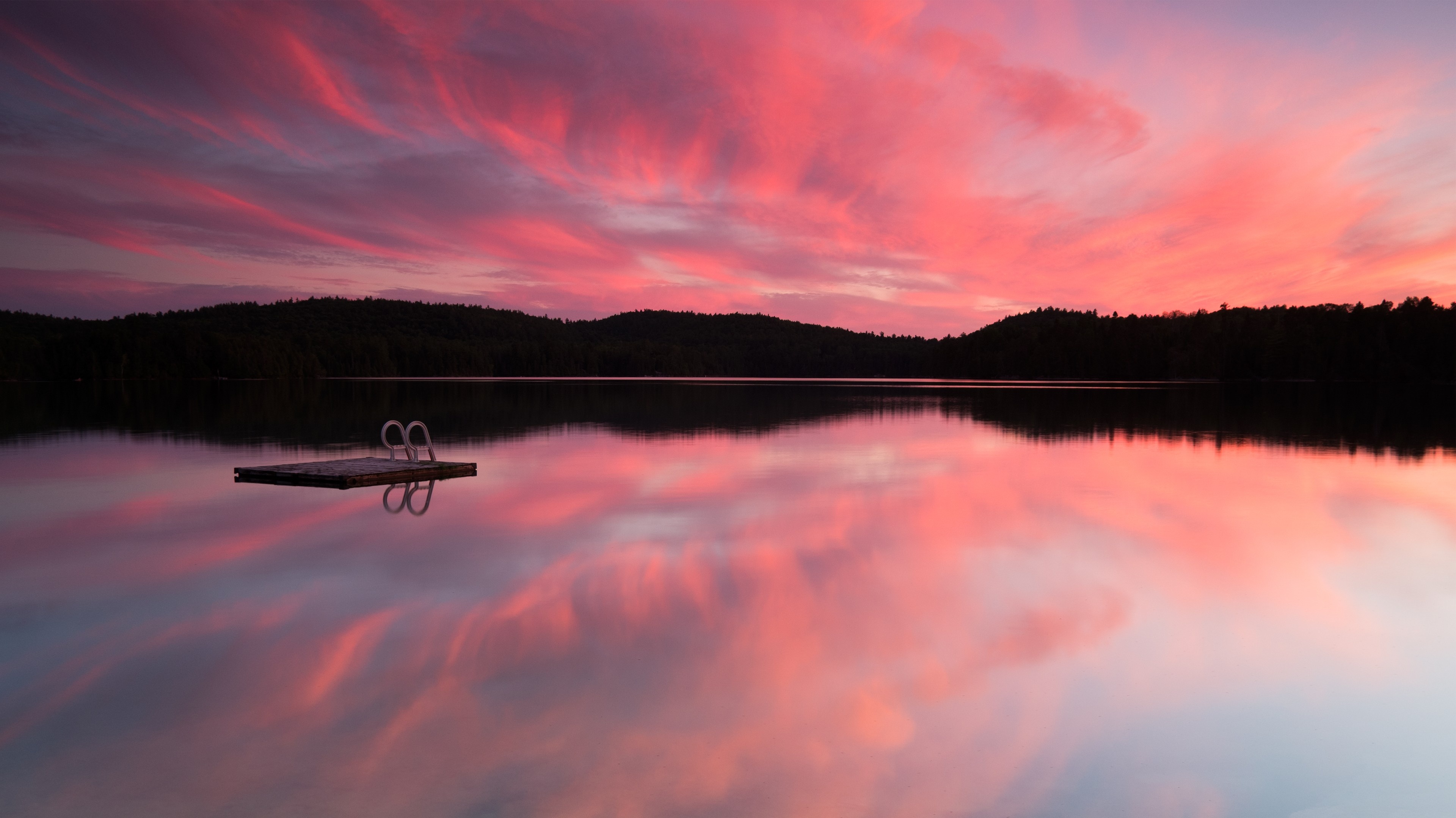 floating dock with ladder, pink sunset cloud reflection, forested lake shoreline, 4K Desktop wallpaper