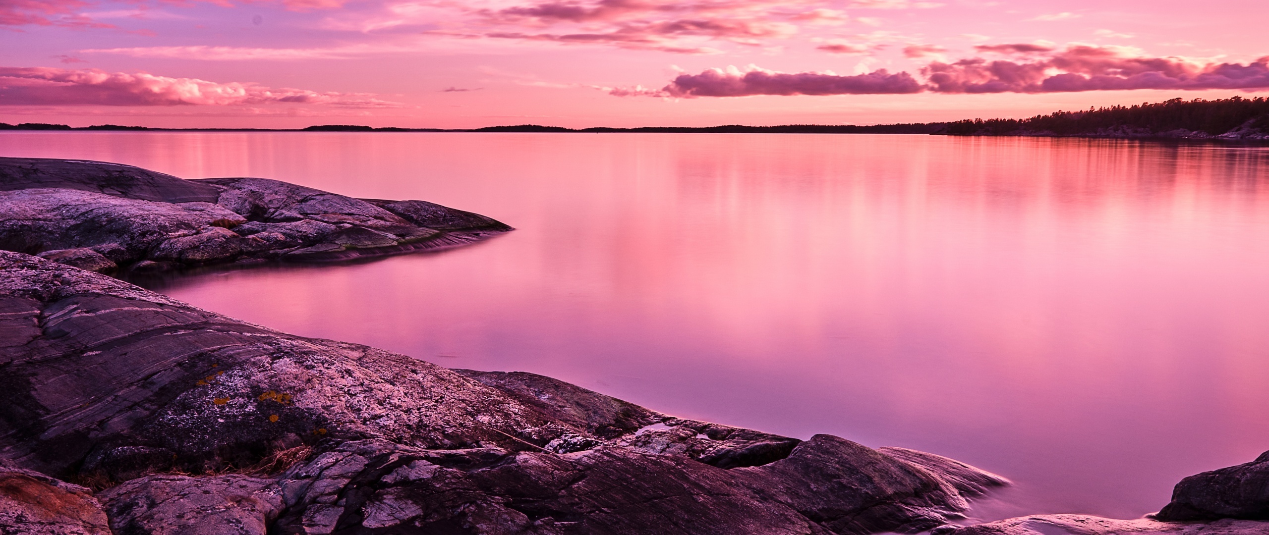 smooth granite rocky shoreline, calm pink twilight water, pink dusk sky clouds, Dual Screen Desktop wallpaper