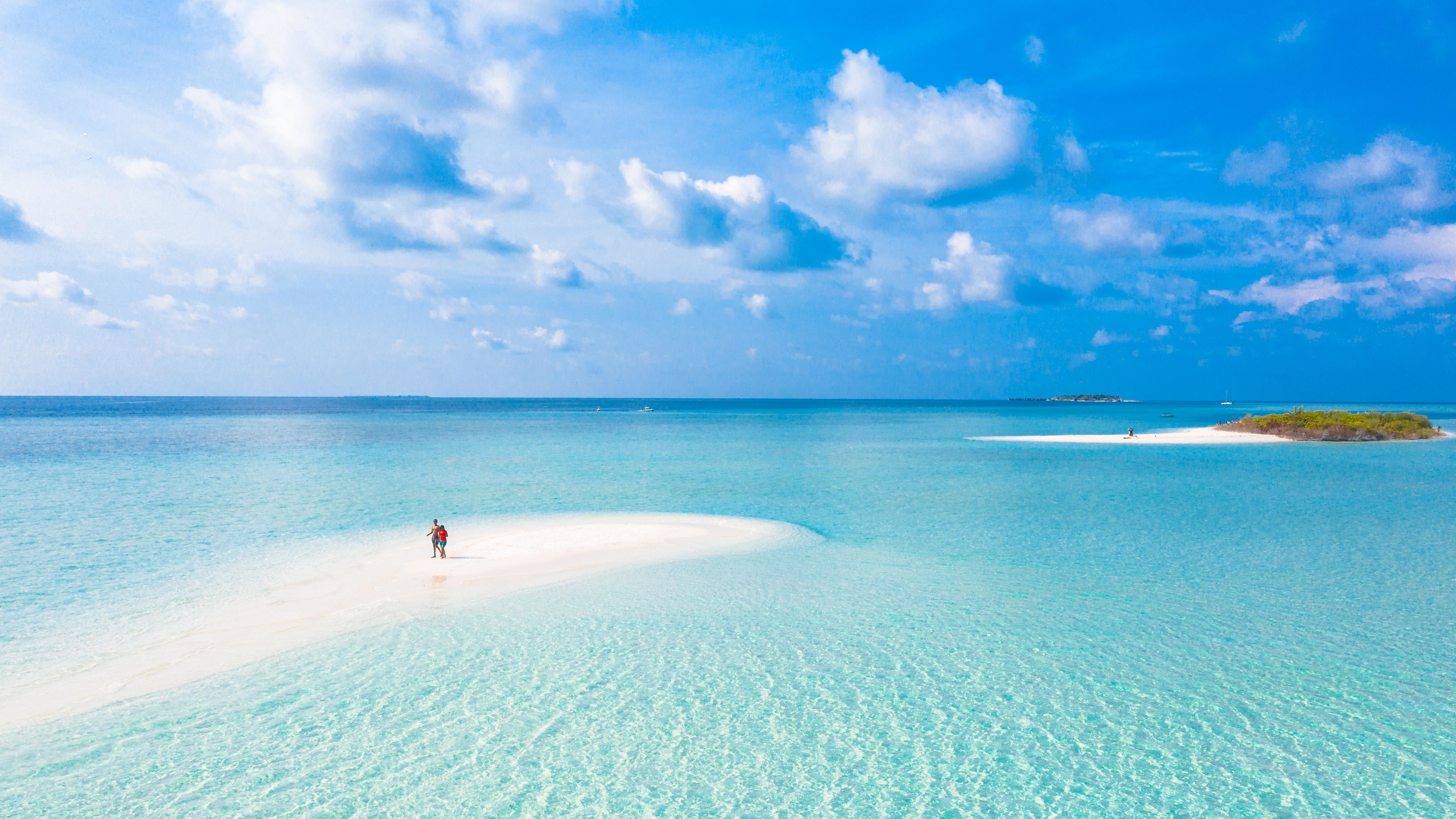 couple on tropical sandbar, clear turquoise lagoon, blue sky cumulus clouds, 4K Desktop wallpaper