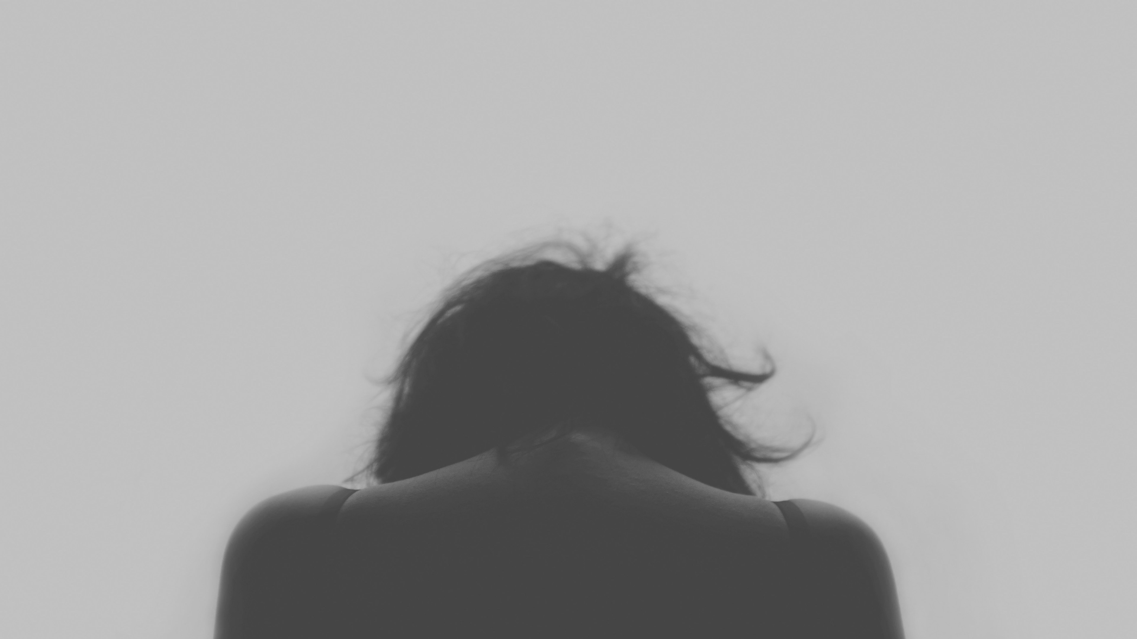 Person with bowed head, Disheveled dark hair, Minimalist monochrome background, 4K Desktop wallpaper