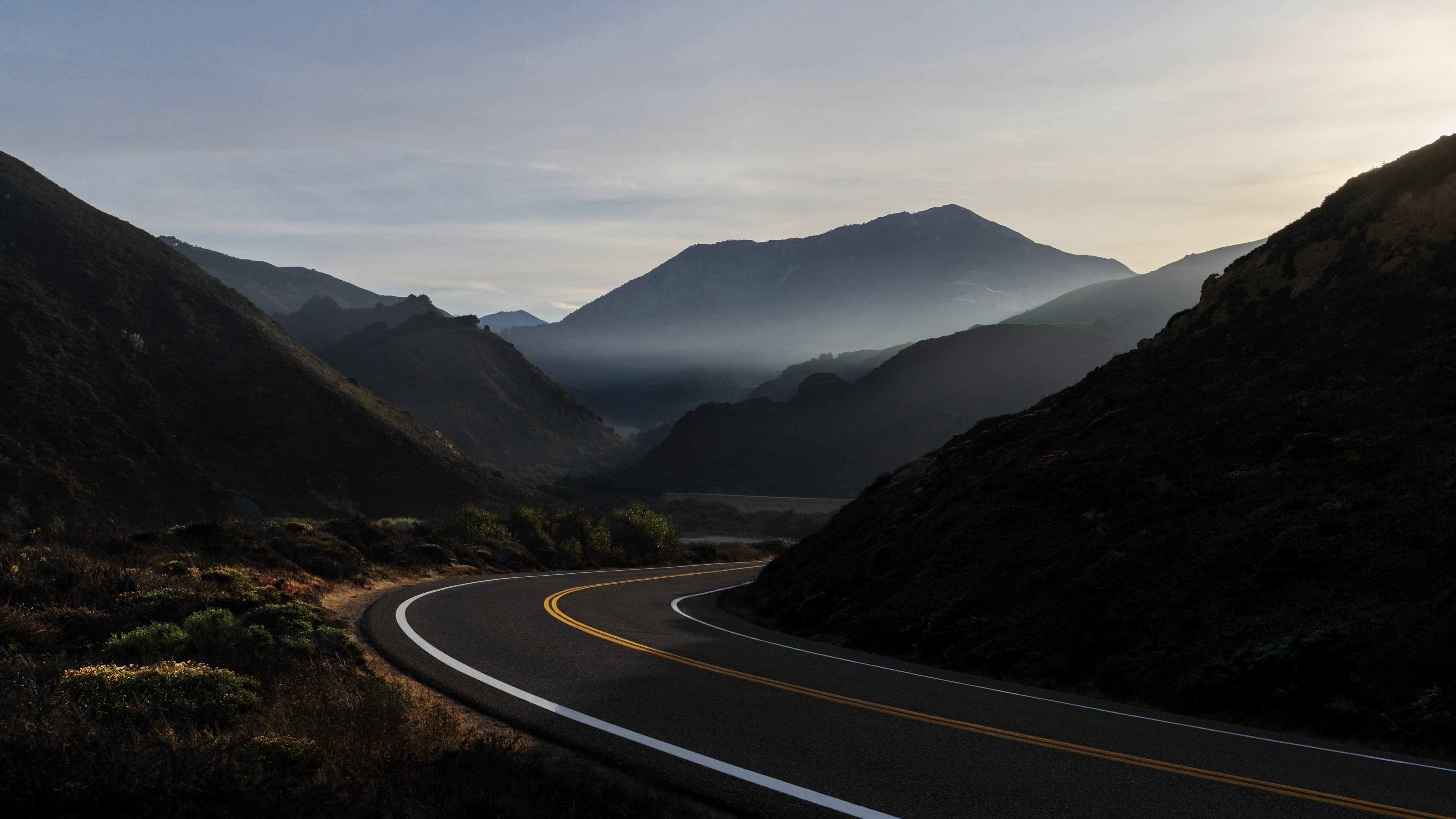 winding two-lane asphalt road, misty mountain valley, distant mountain peak, 4K Desktop wallpaper