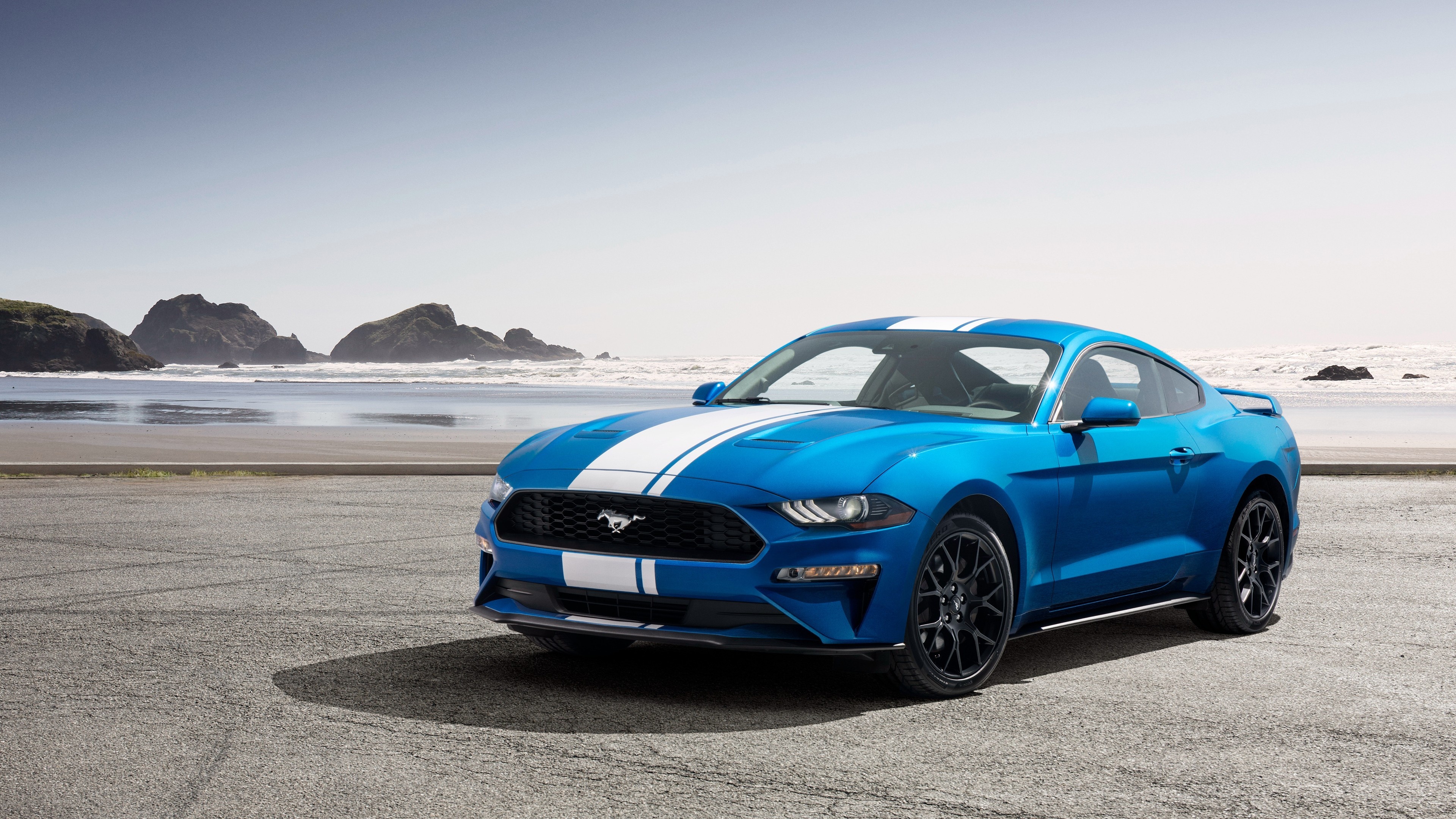 blue Ford Mustang coupe, white racing stripes, rocky coastal beach, 4K Desktop wallpaper