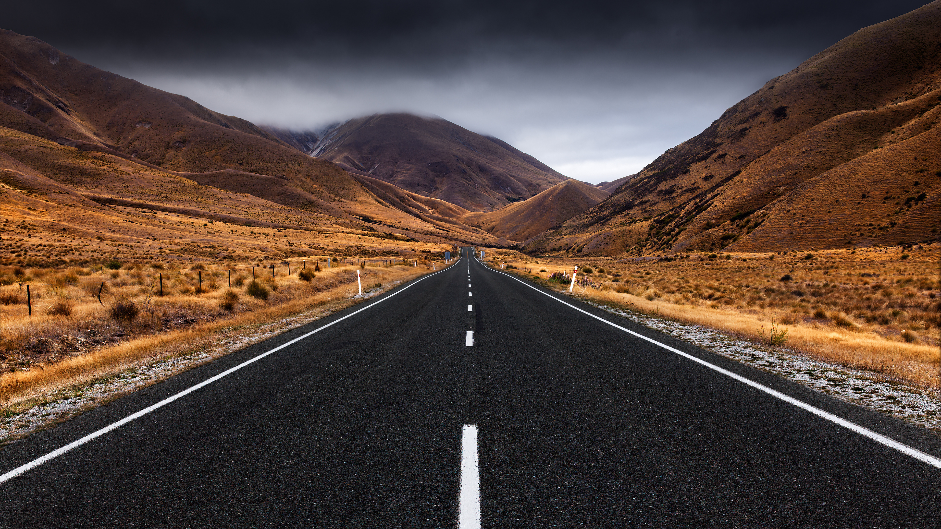 Lindis Pass highway, golden tussock mountains, dark storm clouds, 4K Desktop wallpaper