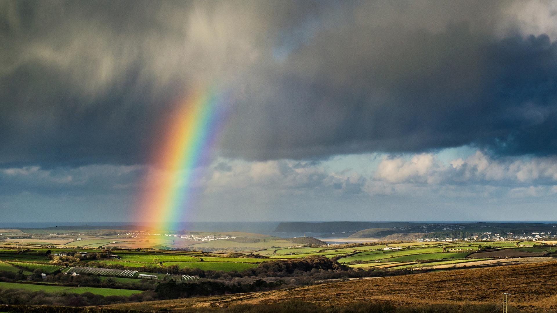 Rainbow over green farmland, Rolling patchwork countryside, Dark stormy sky, Full HD Desktop wallpaper