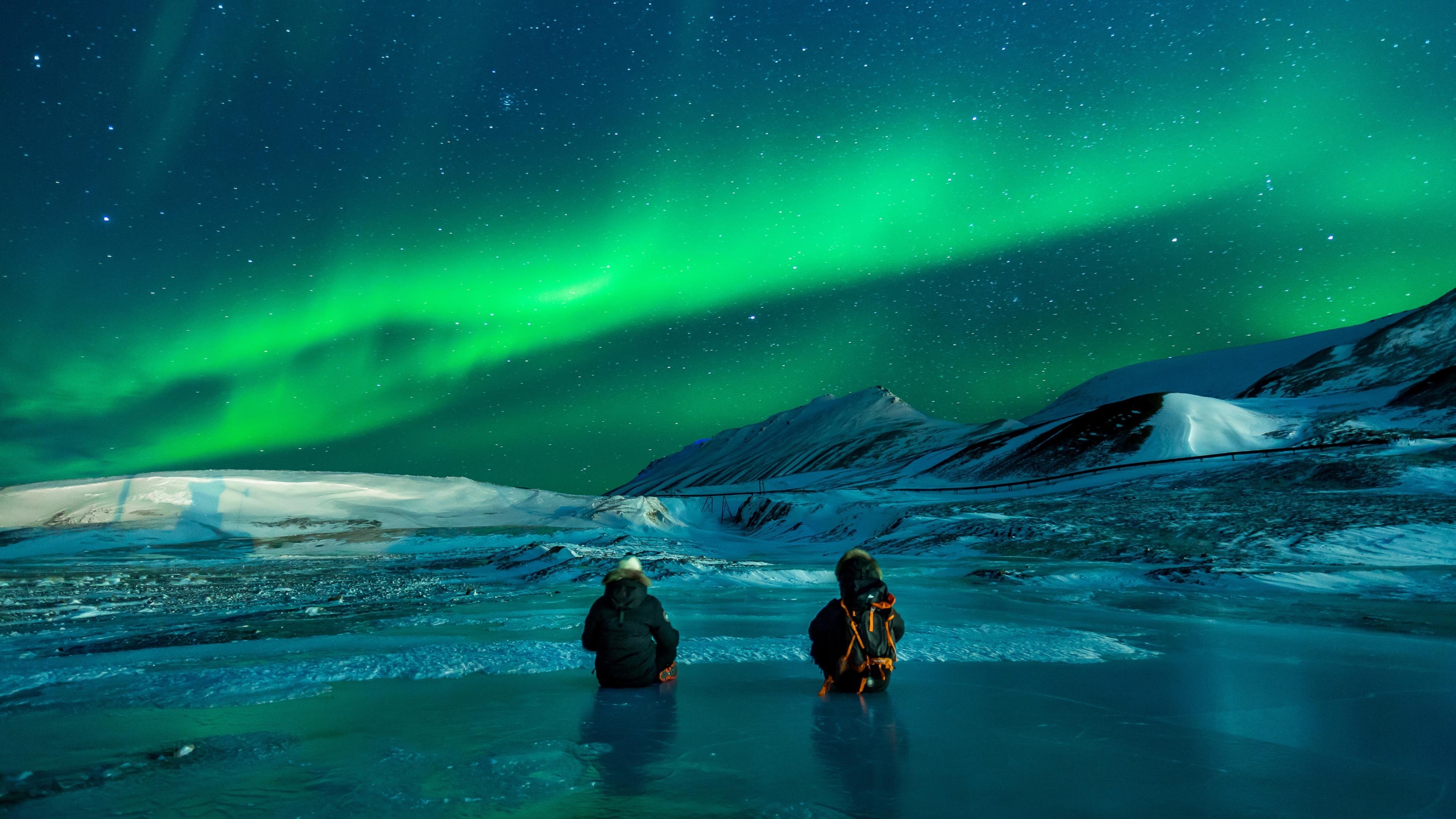 Green Aurora Borealis ribbon, Two stargazers on ice, Snowy Arctic mountain range, 4K Desktop wallpaper