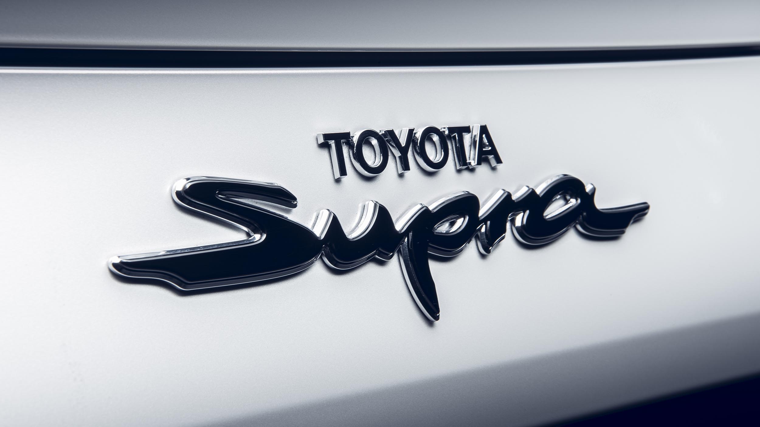 Toyota Supra emblem, Black Supra script lettering, White car body panel, HD Desktop wallpaper